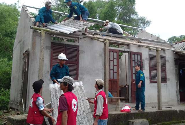 Các tình nguyện viên CTĐ và dân quân xã Hải Thành lợp nhà cho bà Phan Thị Hường